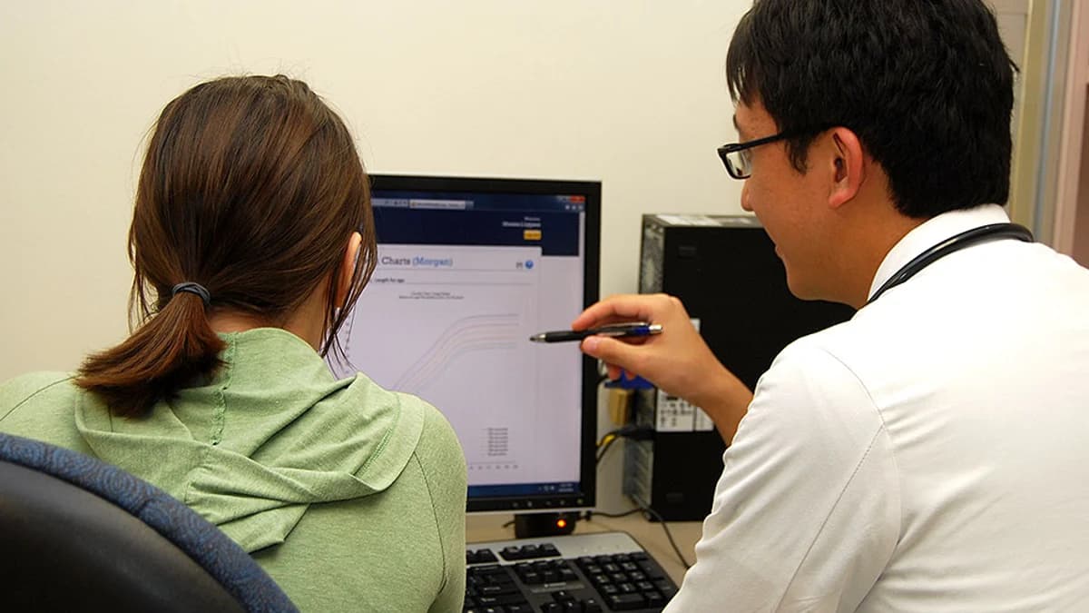 Médico e paciente revisam informações clínicas em um computador
