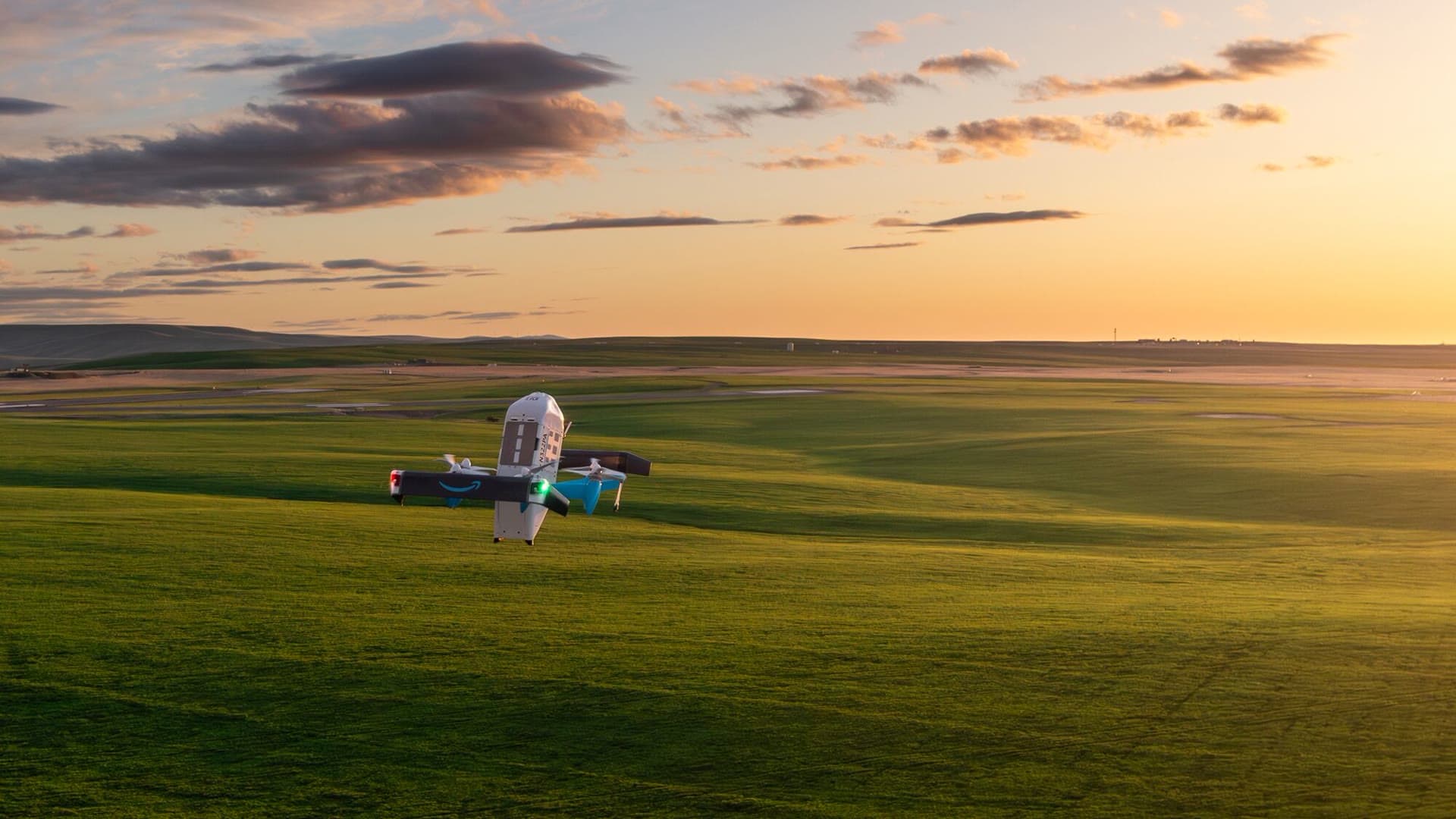 Drone MK30 da Amazon Prime Air voa sobre uma área rural ao pôr do sol
