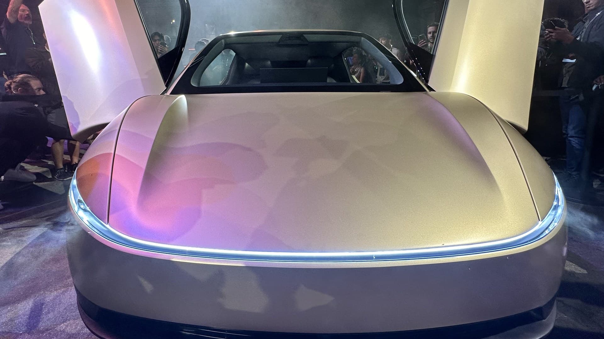 Vista frontal de um Tesla Cybercab dourado com as duas portas abertas durante uma apresentação